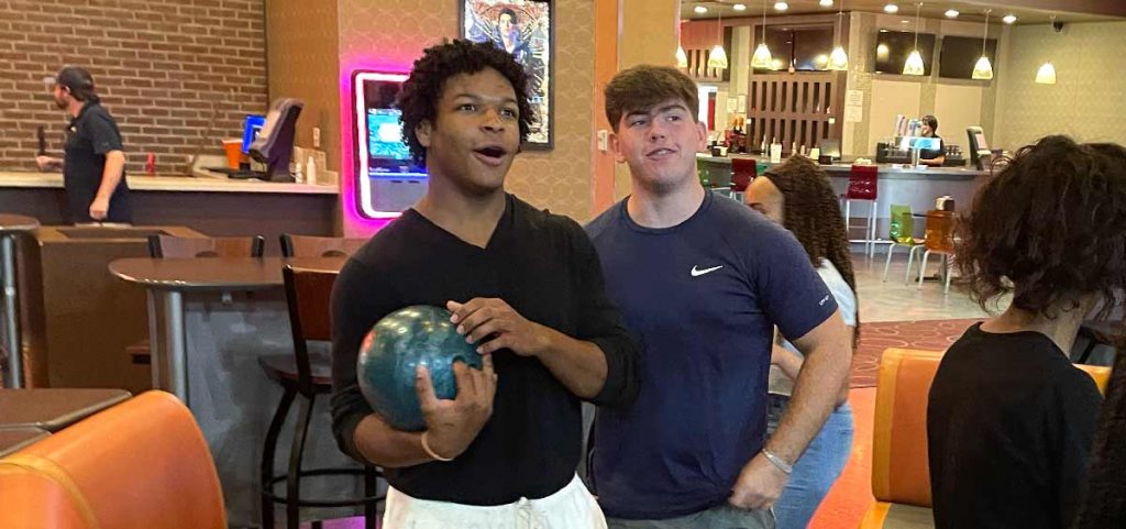 Students at bowling alley. One student holds a bowling ball.